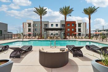 A pool surrounded by lounge chairs and palm trees.